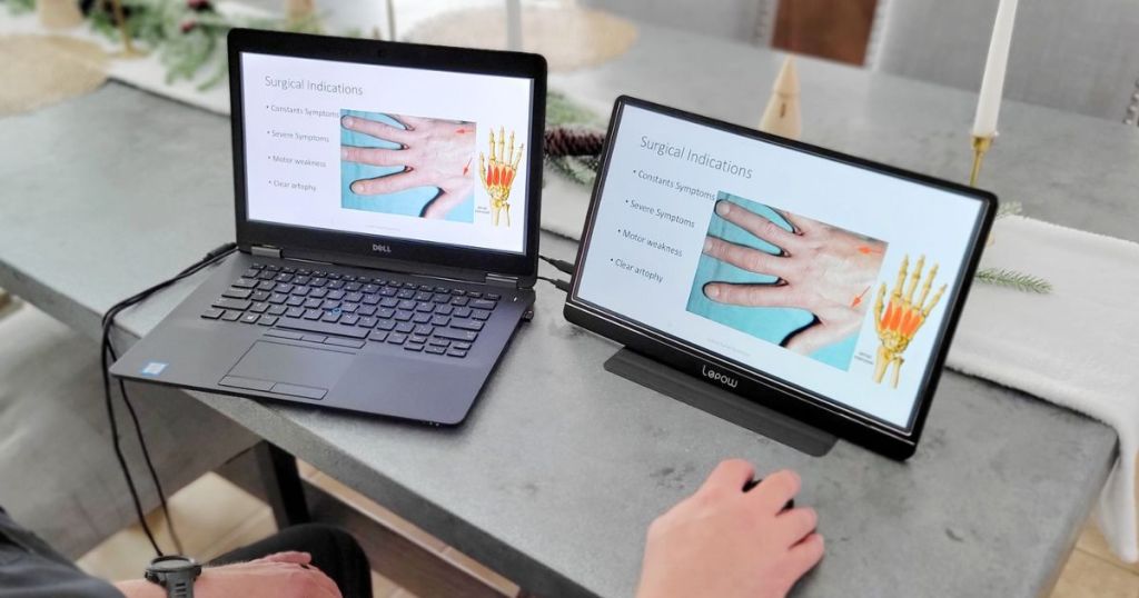 A laptop and the Lepow Portable monitor next to each other on a desk with a man using a mouse to control the monitor