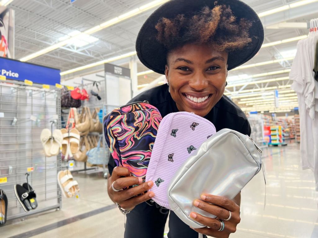 A woman holding 3 fanny packs in a store