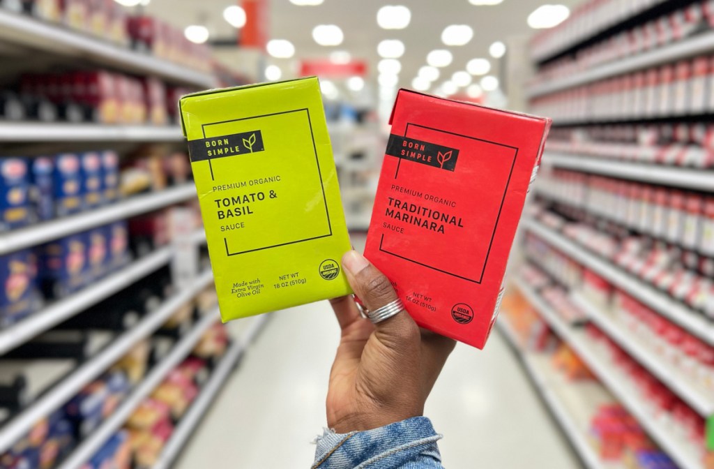 hand holding up two born simple pasta sauces in a target store aisle