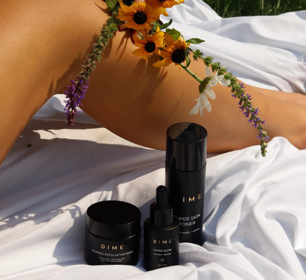 skincare products on picnic blanket next to woman's legs