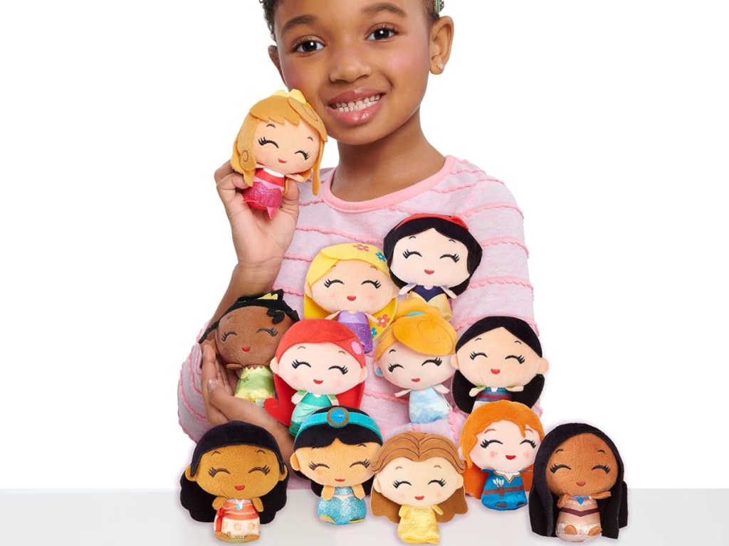 young girl behind 12 disney princess plush dols