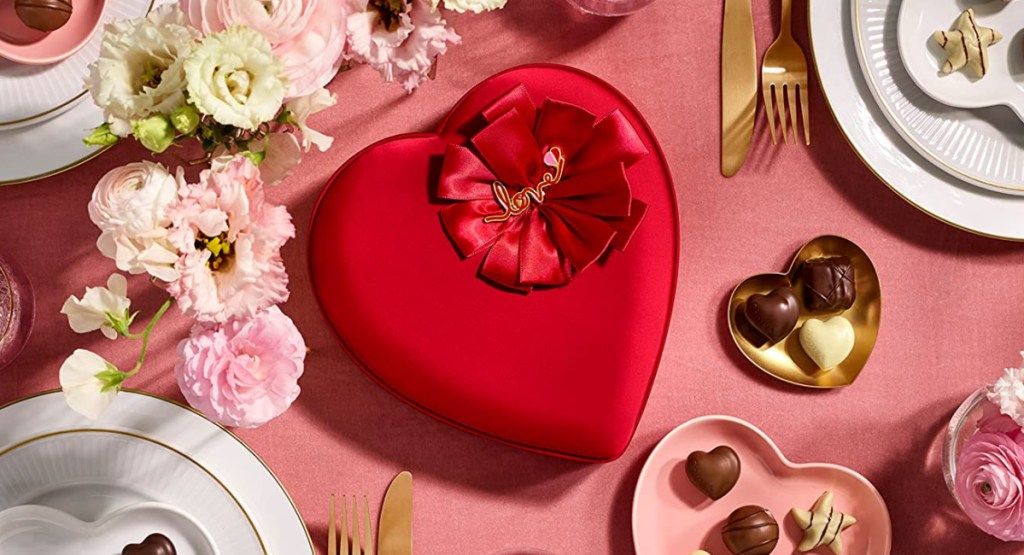 heart shaped chocolate box on table surrounded by flowers