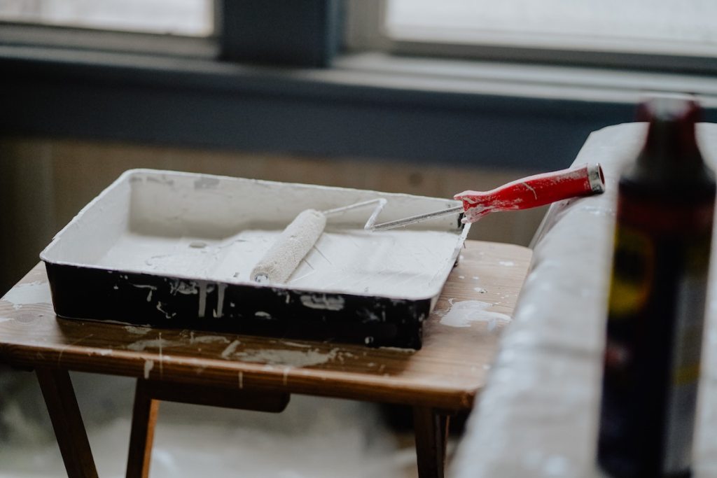 paint roller on wood table with white paint for home renovation tips