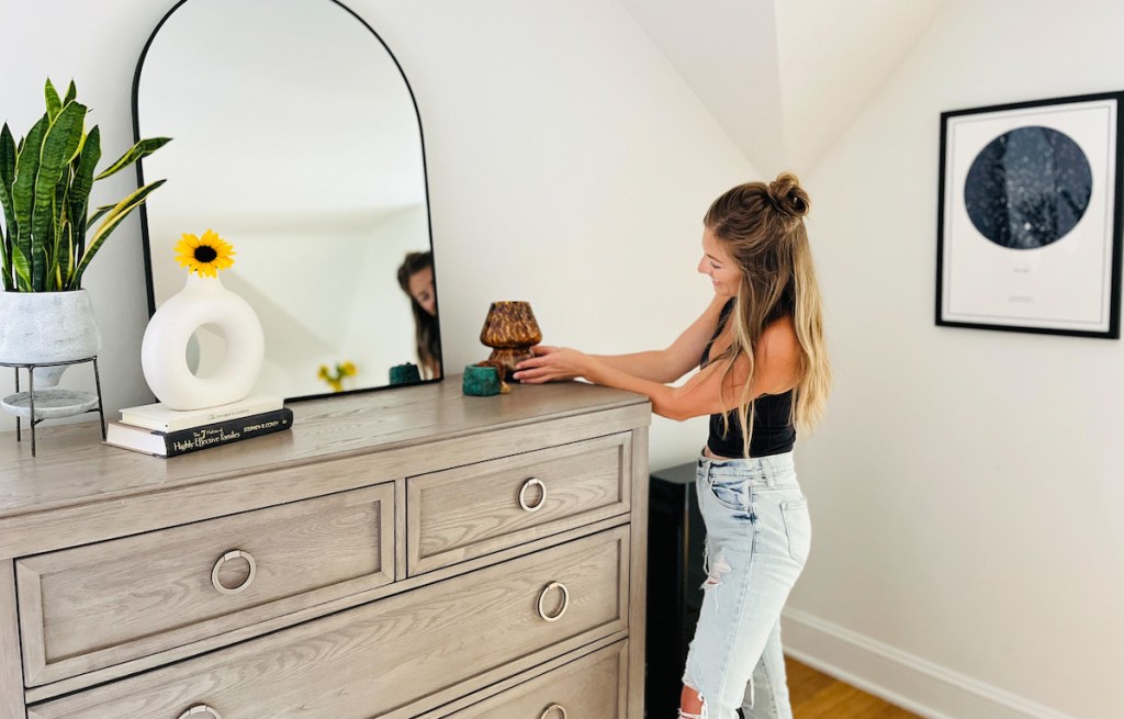 woman putting mushroom lamp on dresser