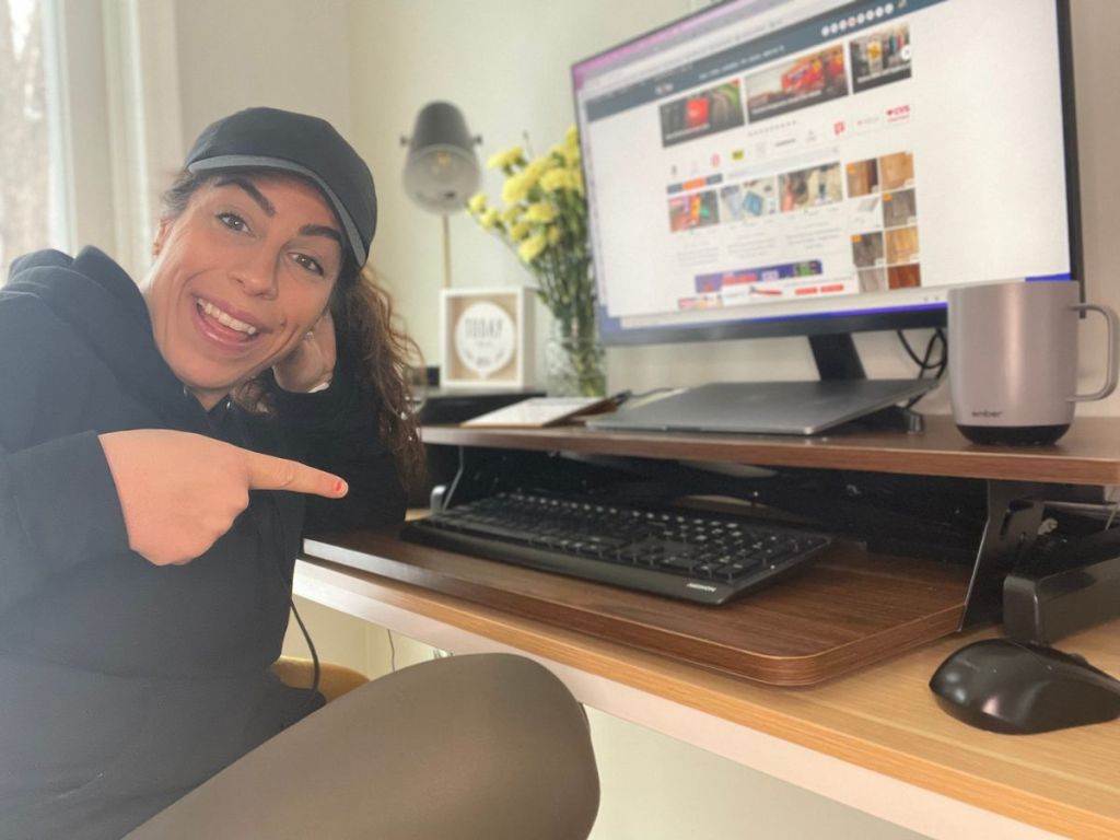 woman pointing at HappYard Desk Converter in lowered position