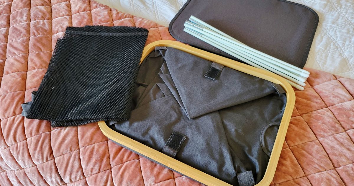 collapsible laundry basket folded down laying on bed