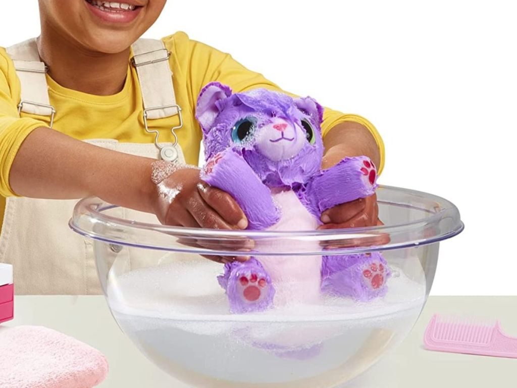 Girl holding a plush toy cat in a bowl of water