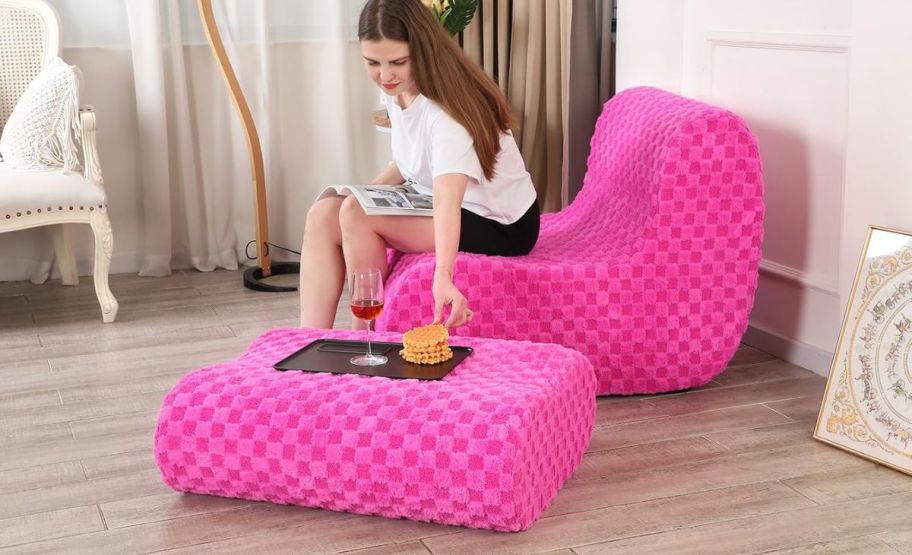 a woman with a book sitting on a pink bean bag chair