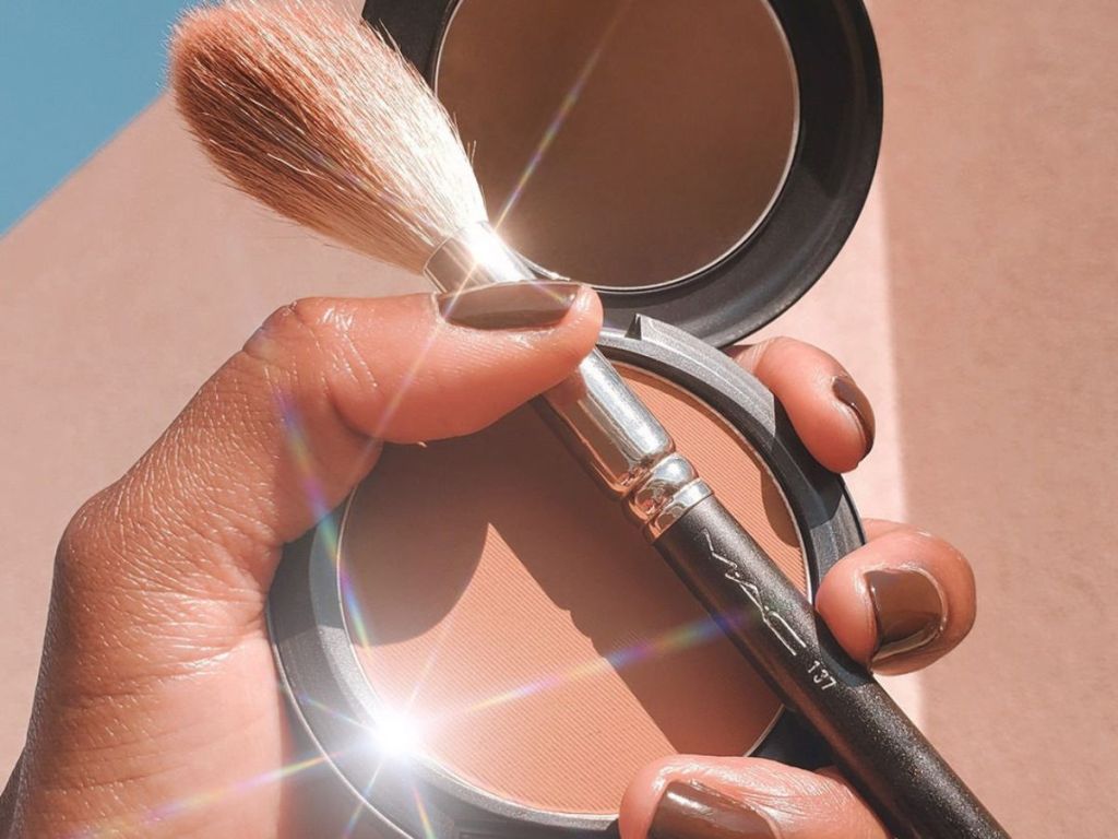 hand holding up an open Mac Studio Fix Powder Foundation onlinepact with a mac makeup brush