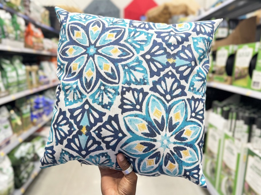 hand holding a blue and white floral print throw pillow