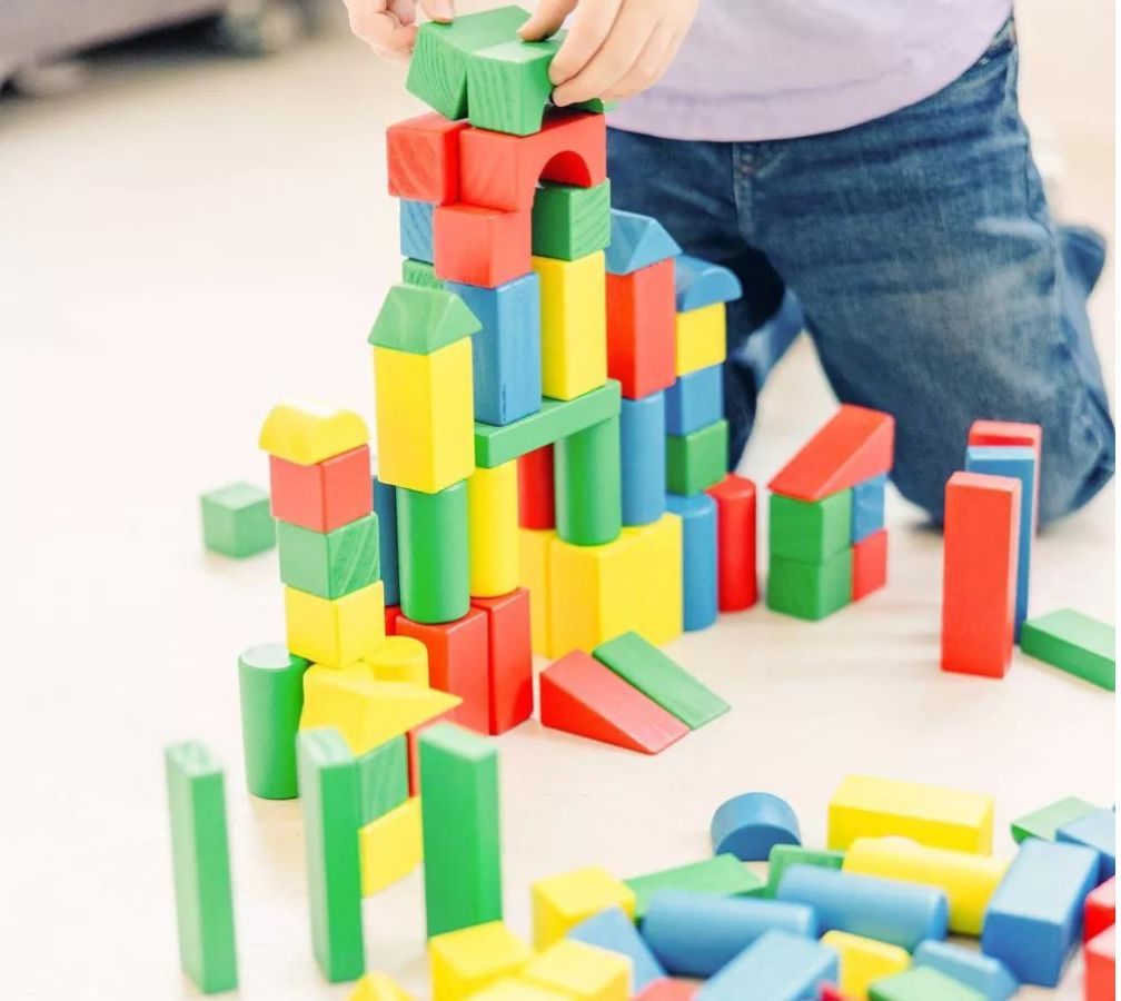 Child playing with Melissa & Doug wooden blocks on the floor