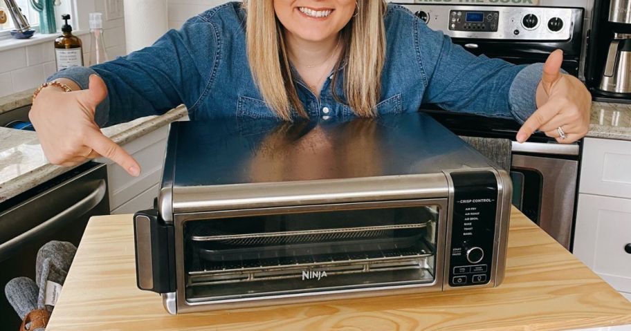 woman pointing with both hands at the Ninja Foodi Air Fryer Oven