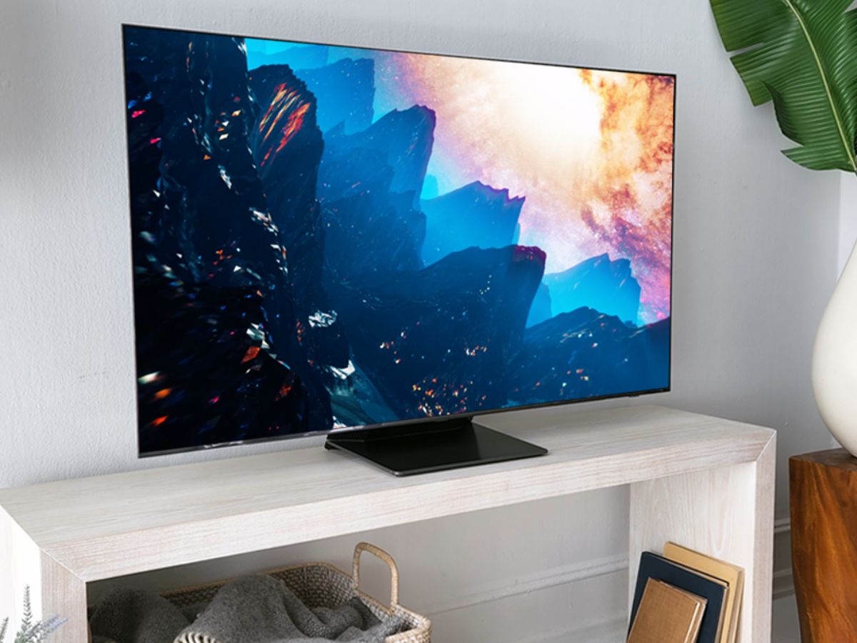 A samsung TV on a shelf next to a large plant