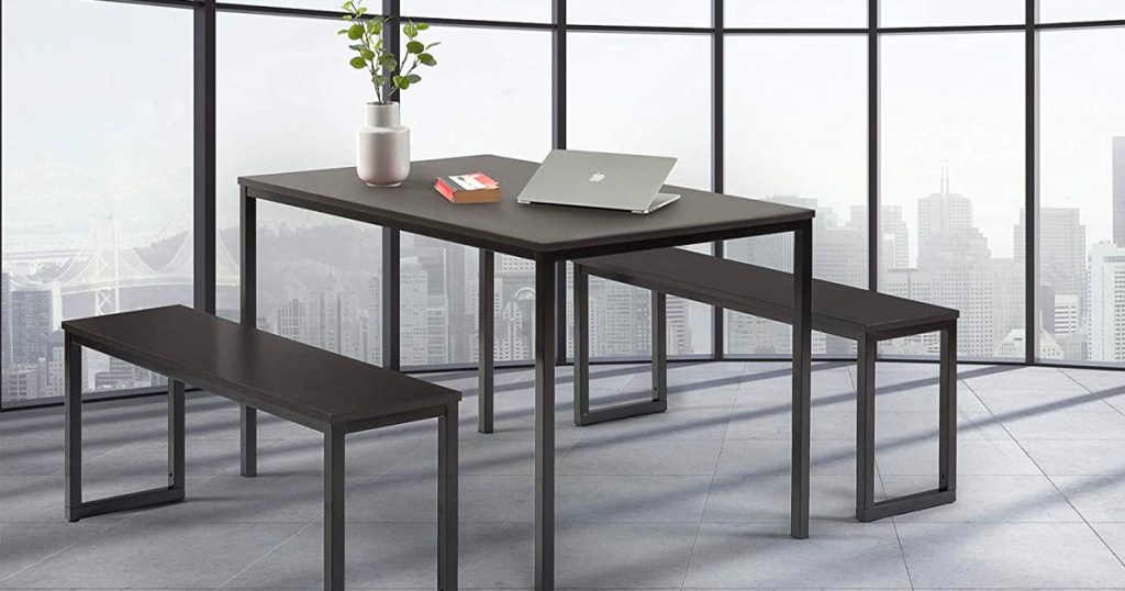 modern black dining table with two benches with laptop and plant on top