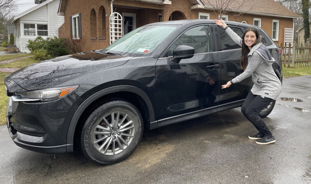 woman standing next to black car outside in rain