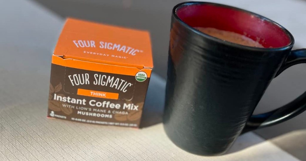 four sigmatic coffee box sitting next to a black coffee mug