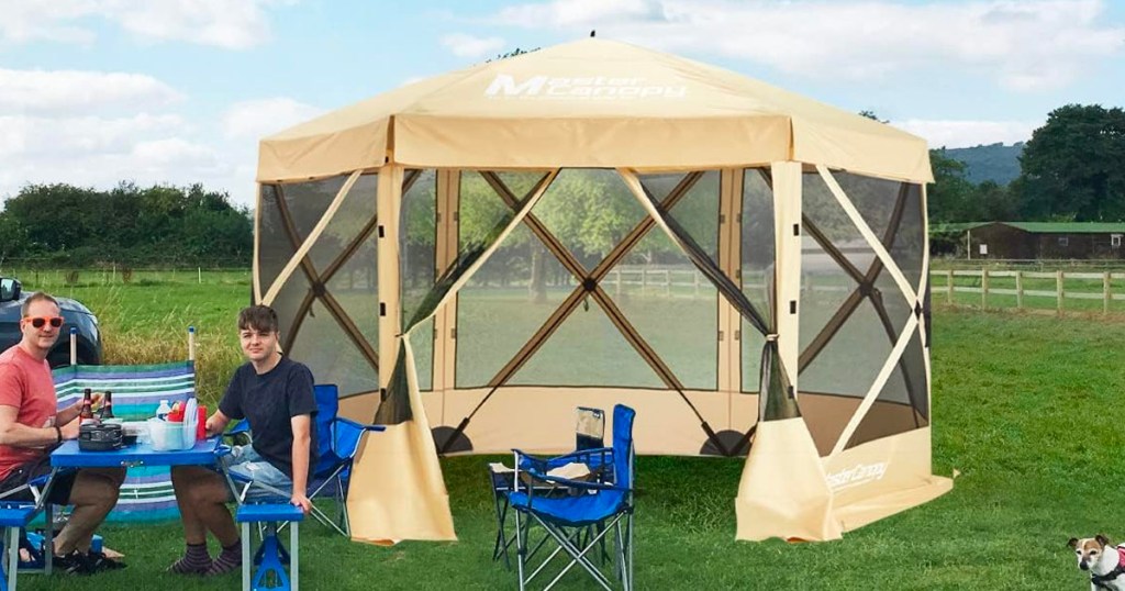 tan mastercanopy shelter with two men in chairs sitting outside of it