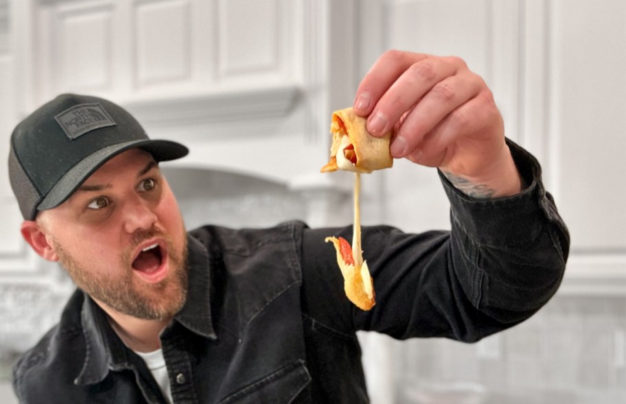 man holding a cheesy crescent pizza roll 