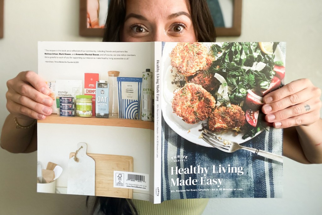 woman with eyes peeking over cookbook