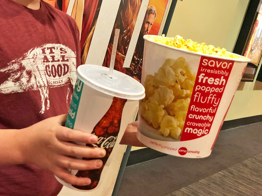 boy holding a bucket of popcorn and drink