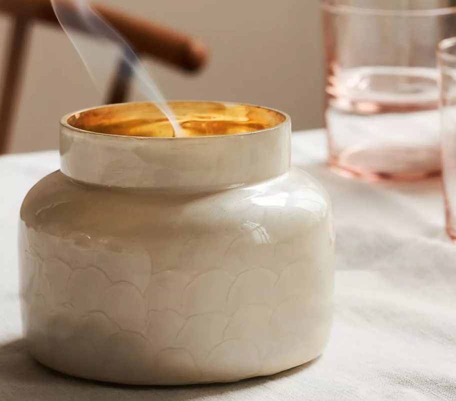 White candle jar with smoke onlineing out the top