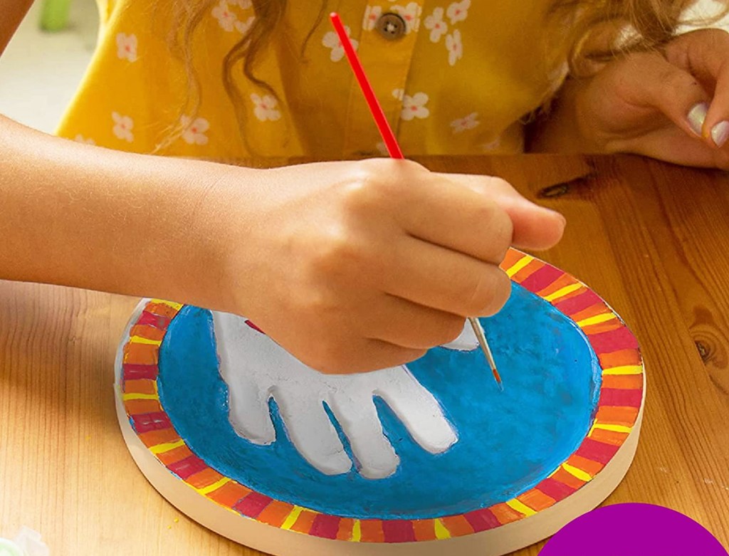 girl painting a handprint stone