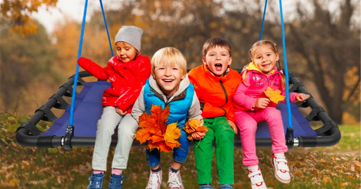 four small children swinging on a giant tree swing 