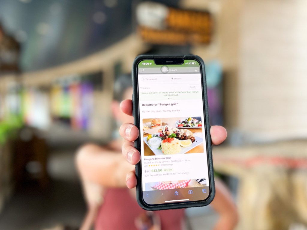 person holding up cell phone featuring groupon restaurant deal