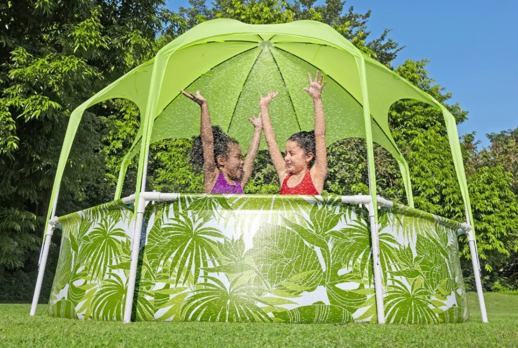 Two girls in a green above-ground pool with a shade on top