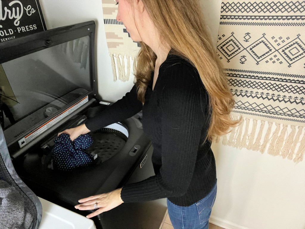Woman placing clothes inside a washing machine