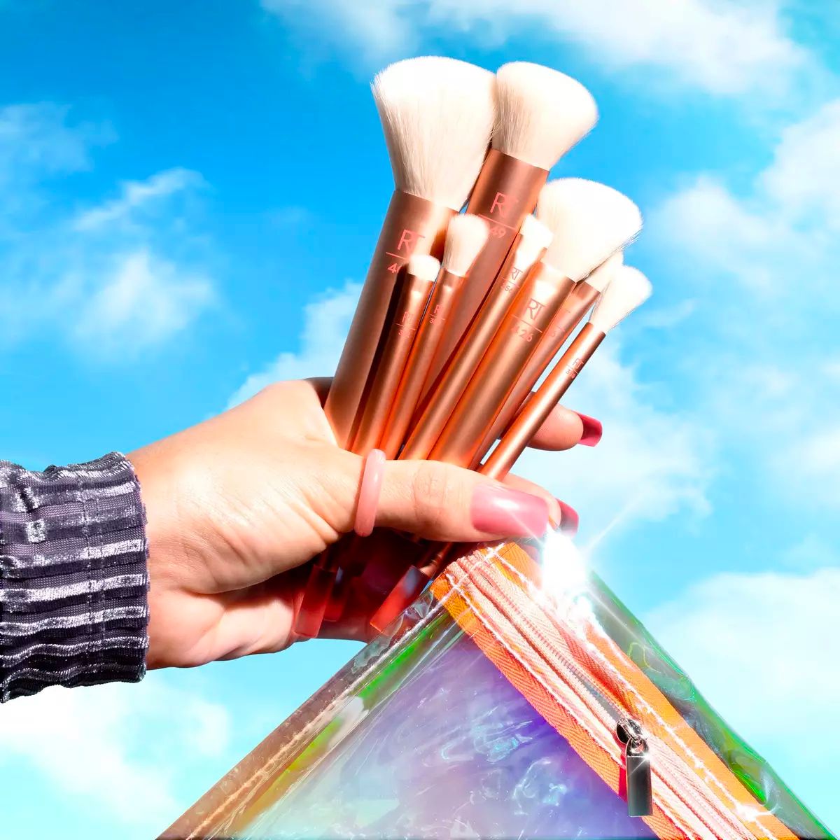 a womans hand holding a Real Techniques The Wanderer Face Makeup Brush Kit and storage bag