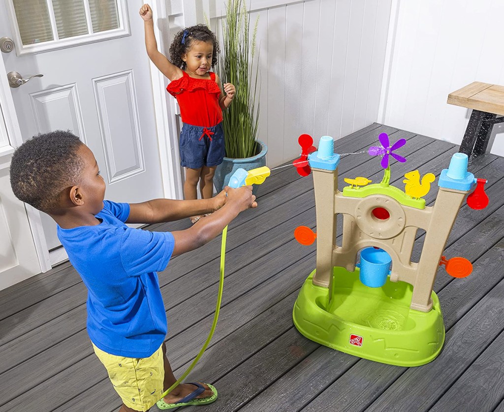 boy aiming garden hose at step2 arcade toy