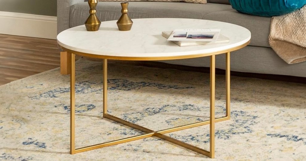 a mid century modern style coffee table with gold legs and a faux white marble top in a living room