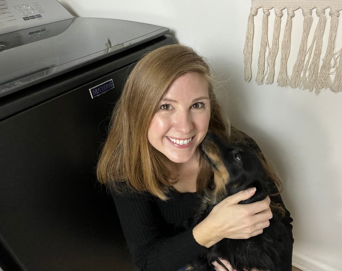 Woman holding her dog next to a Maytag Pet Pro Washer after giving her honest Maytag Pet Pro Washer reviews