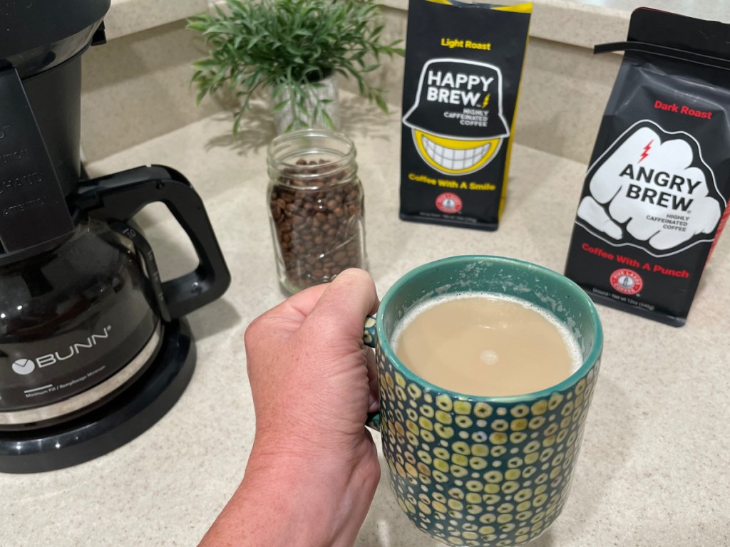 Woman holding coffee cup in front of coffee machine and five lake angry coffee bags