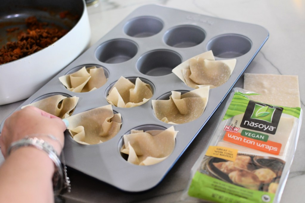 adding wonton paper wraps to a muffin pan