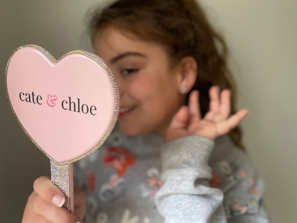 girl holding mirror showing earrings