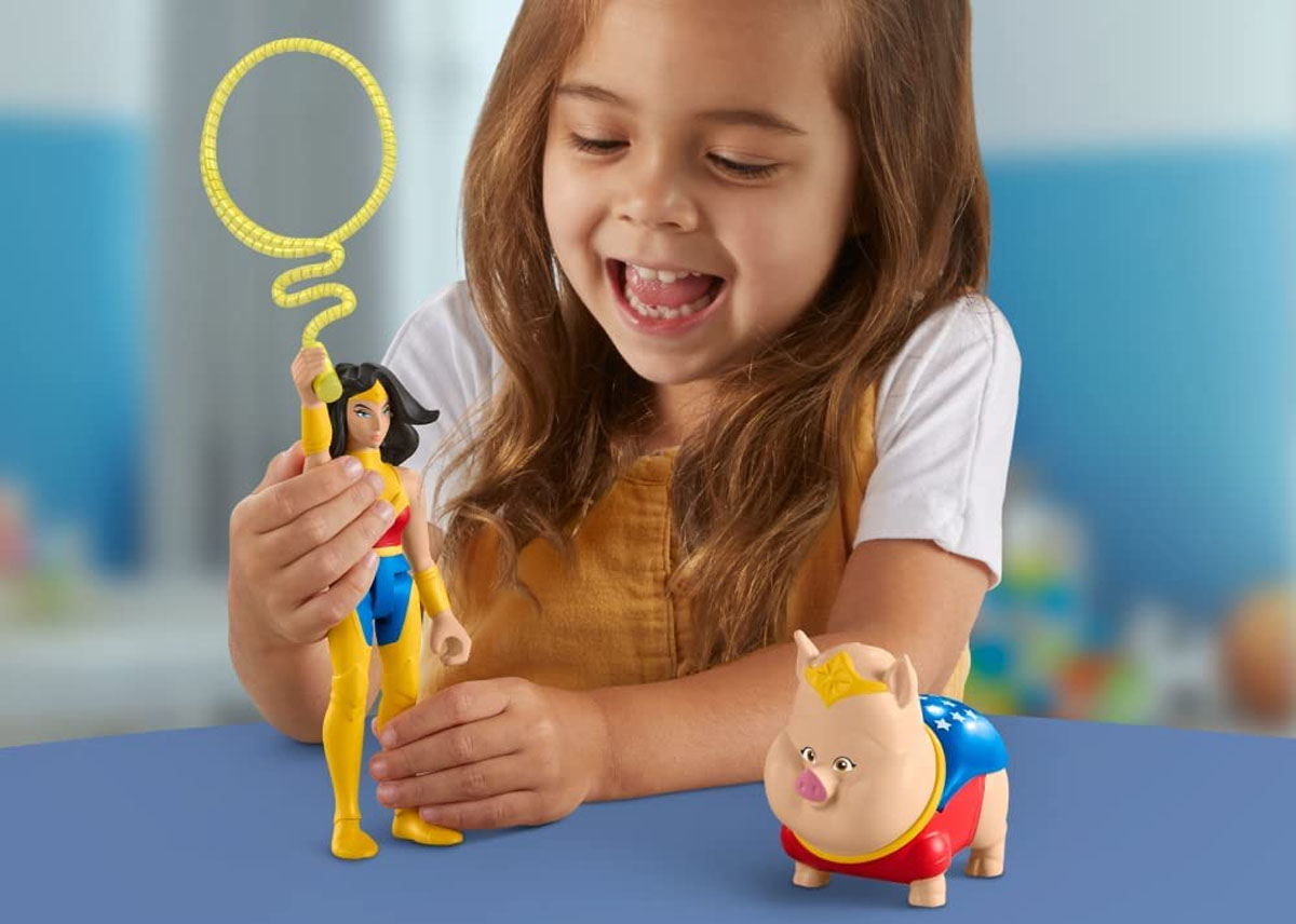 girl playing with wonder woman action figure and pig