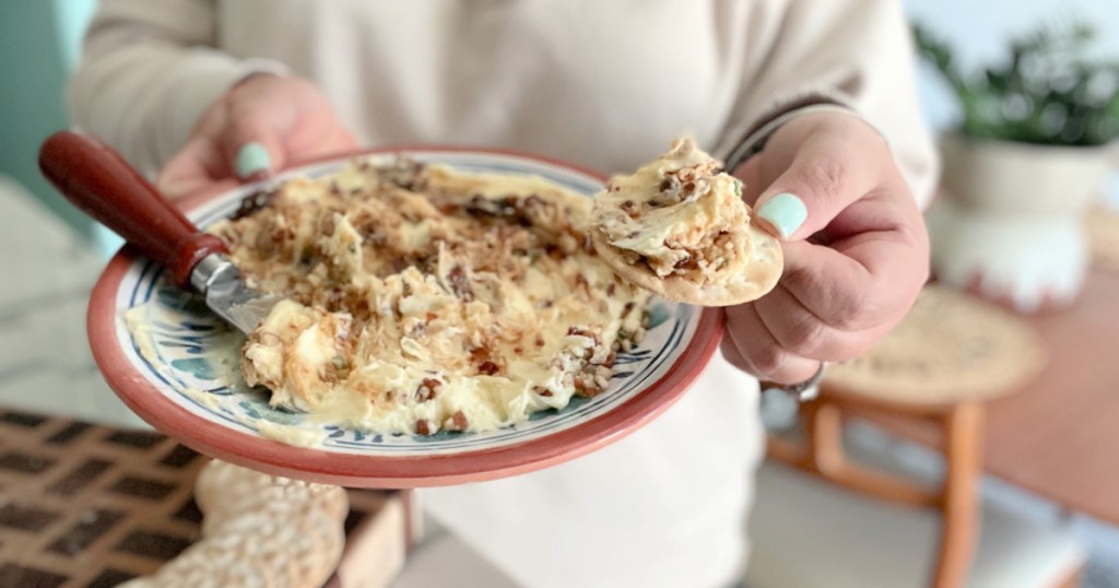 holding a cracker with whipped brie dip