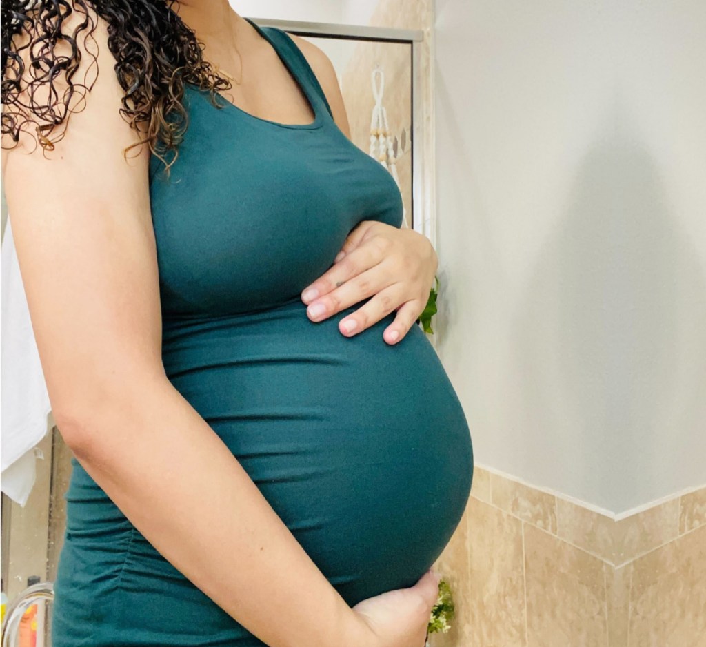 woman in teal dress holding baby bump