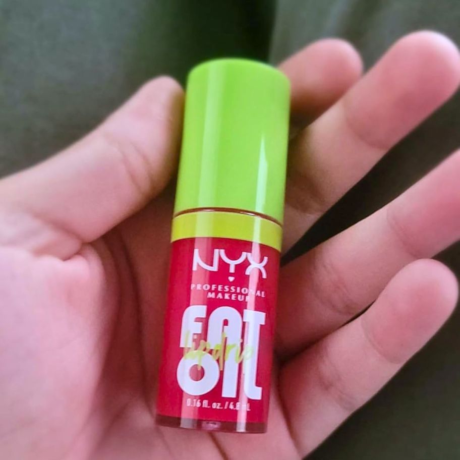 a womans hand holding a tube of NYX fat oil lip oil