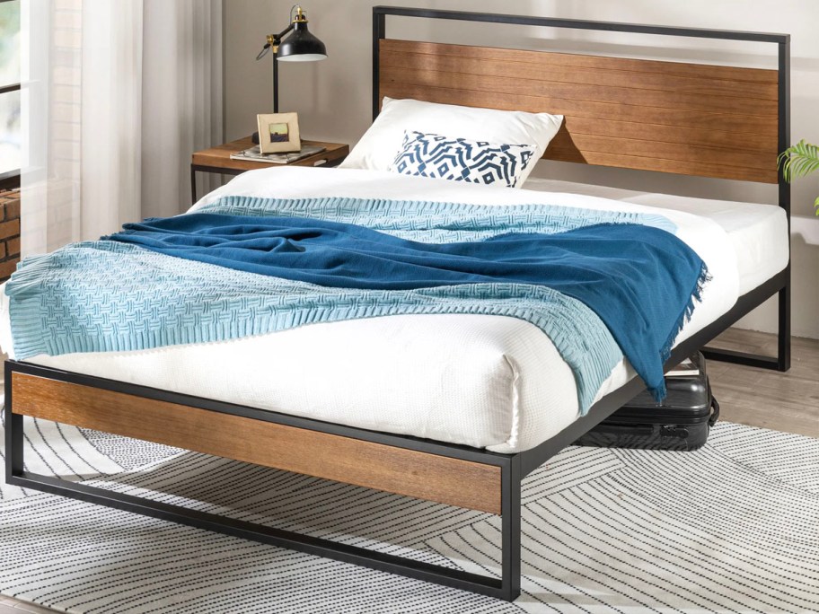 black metal and wood frame bed with blue and white onlineforter set on top