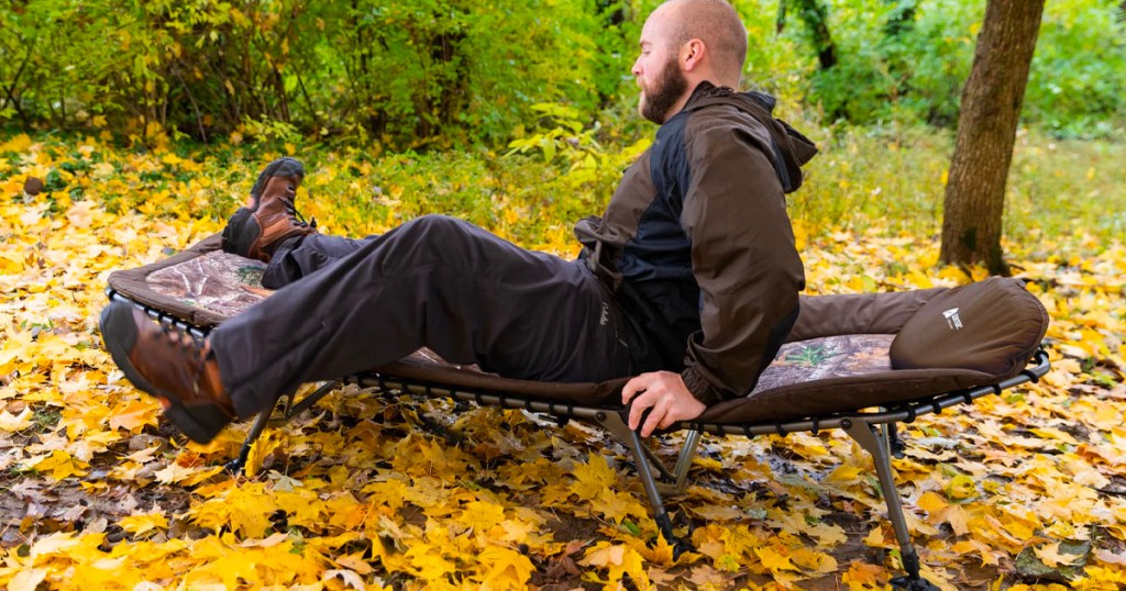 man getting off of camping cot in forest