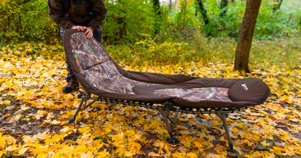 man standing next to camp camping cot in forest