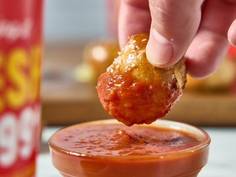 dipping a pretzel bite into marinara sauce