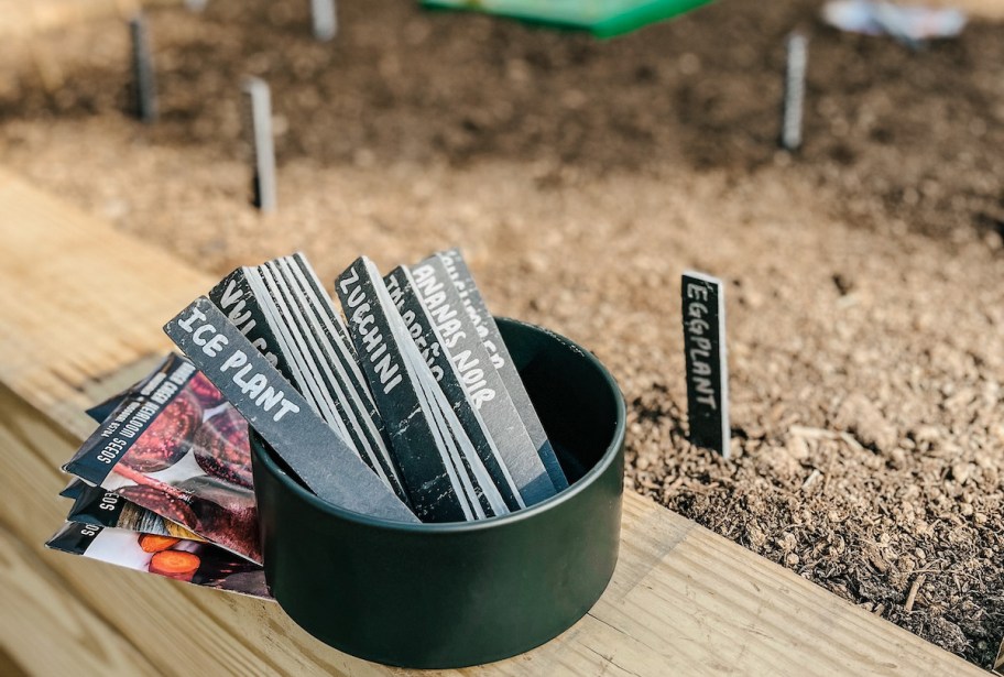 slate garden stakes in bowl on edge of garden bed