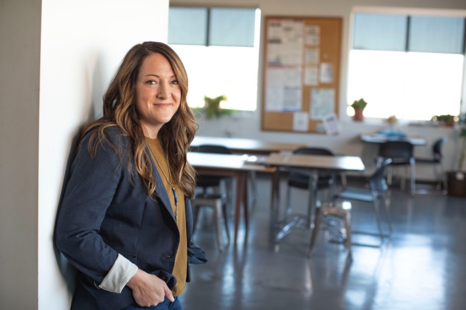 teacher standing in front of empty classroom with desks