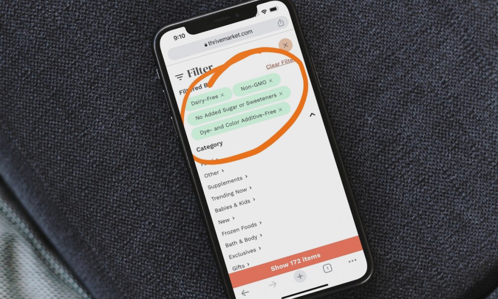 phone sitting on arm of gray couch with thrive market search filters circled on screen