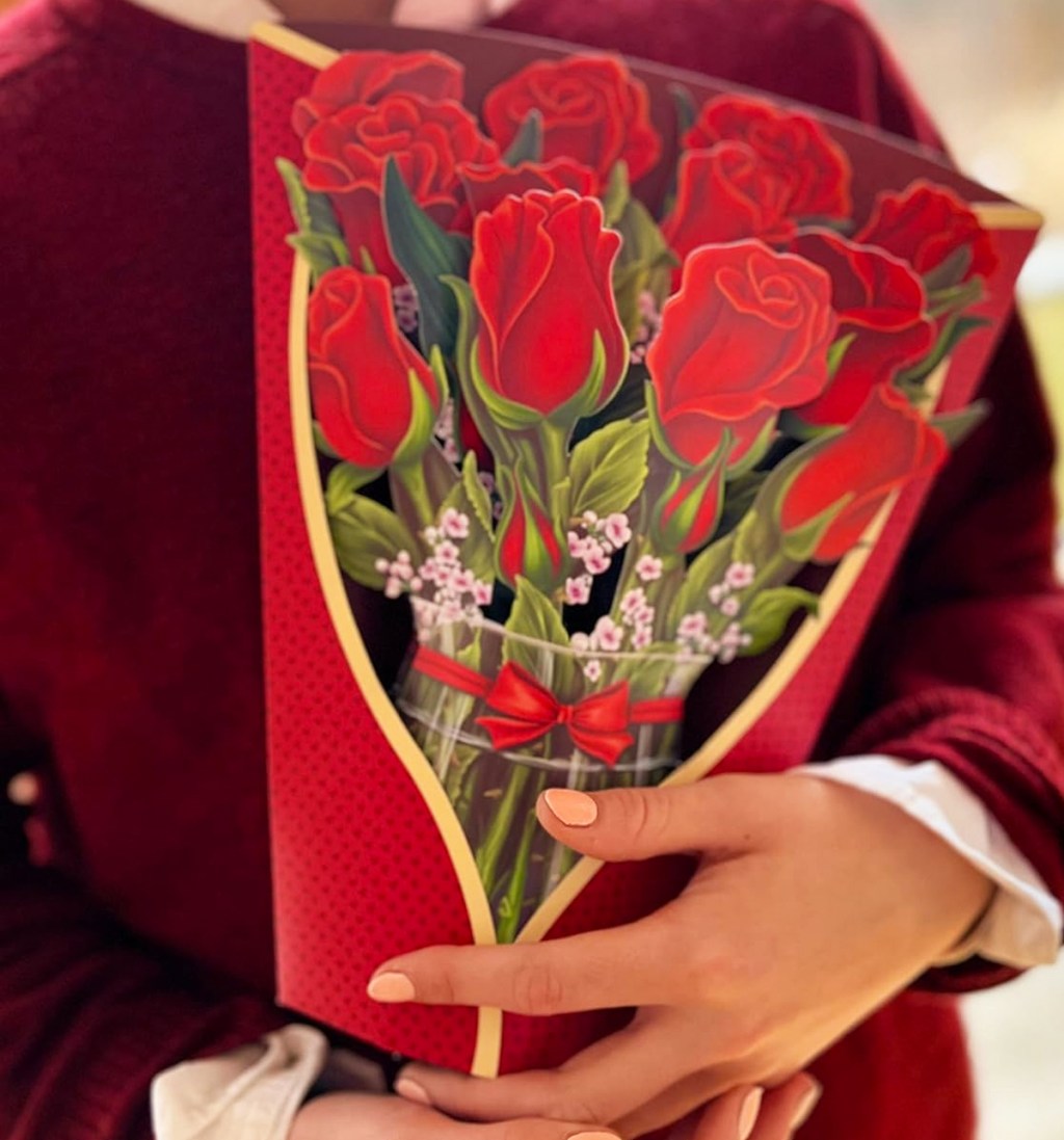 woman holding a paper bouquet of red roses