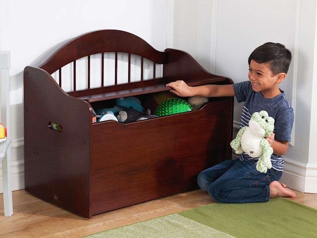 child lifting lid on brown wood toy box bench